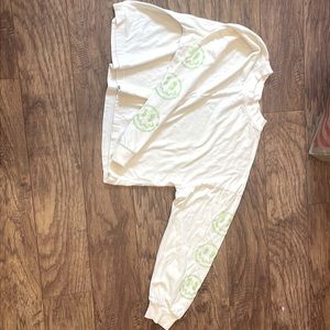 It is a cream shirt with light green smiley faces on it